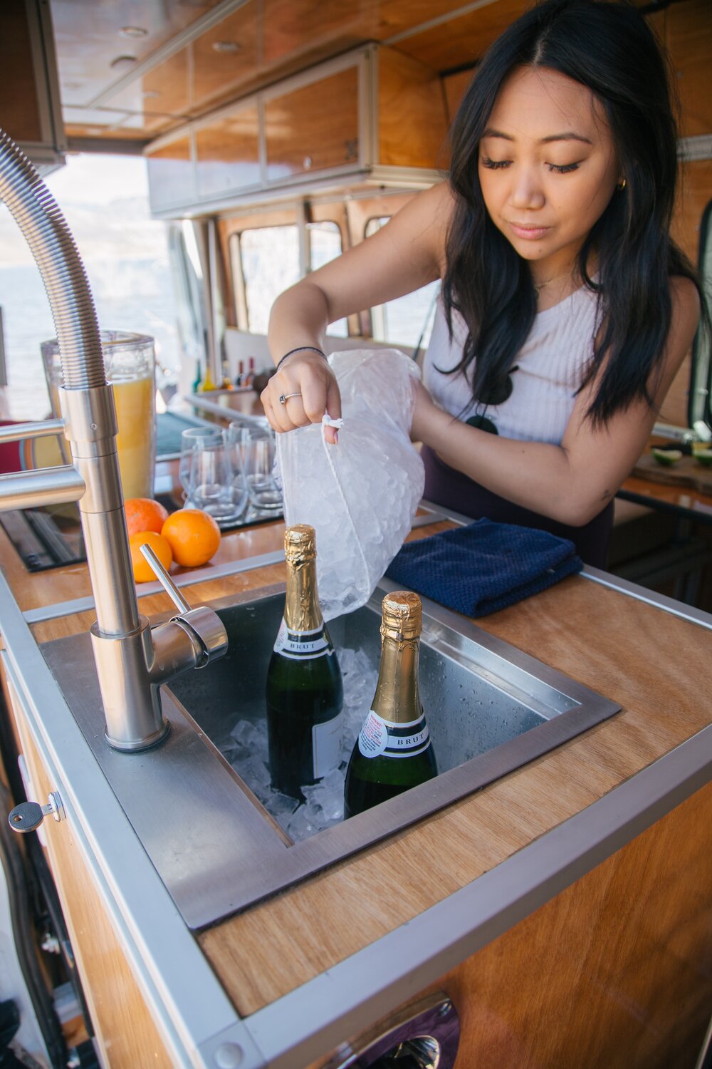 Indulge in refreshing mimosas prepared at the all-in-one kitchen. The sink holds ice and champagne, while oranges and freshly squeezed orange juice are displayed on the flush stove. Glasses are ready to be filled for a delightful treat.