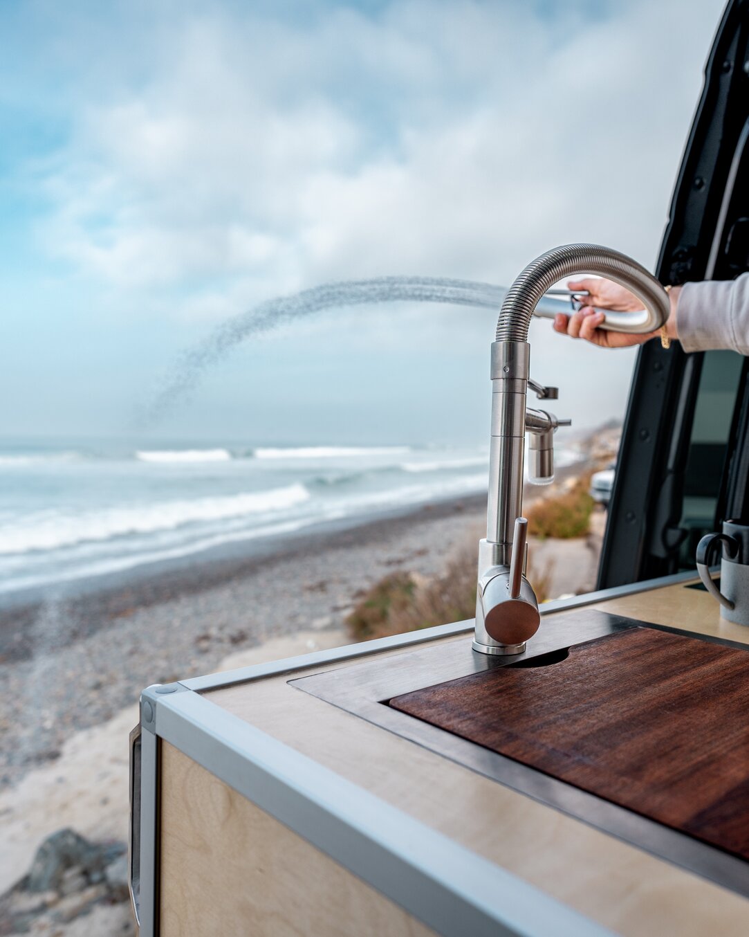 Camper van kitchen faucet spraying out the slider door of the 144 conversion van.