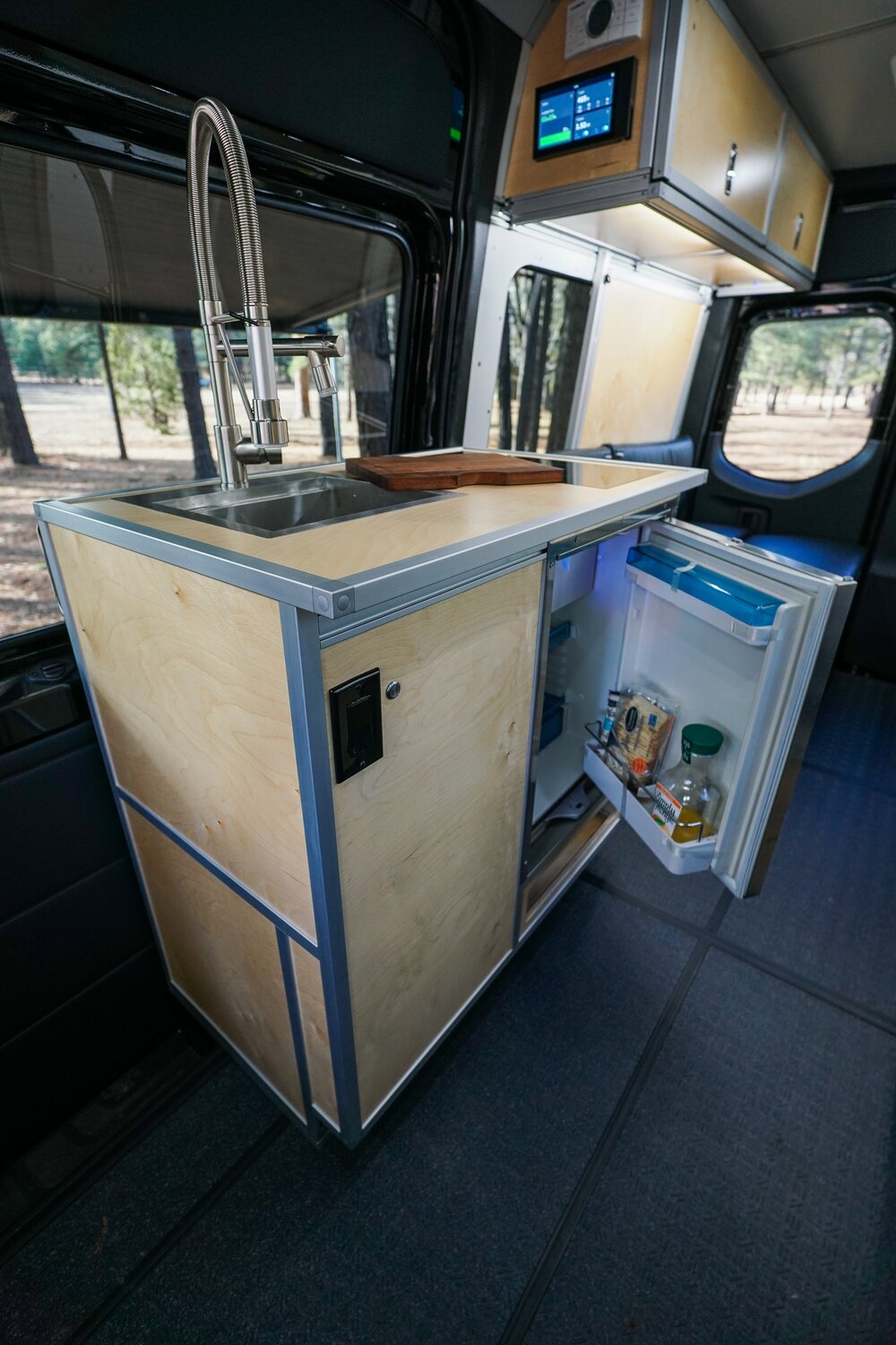 The compact Kitchen galley is shown with the Dometic CRX 80S fridge open, and the controls for the under cabinet lighting and hot water heater are teased