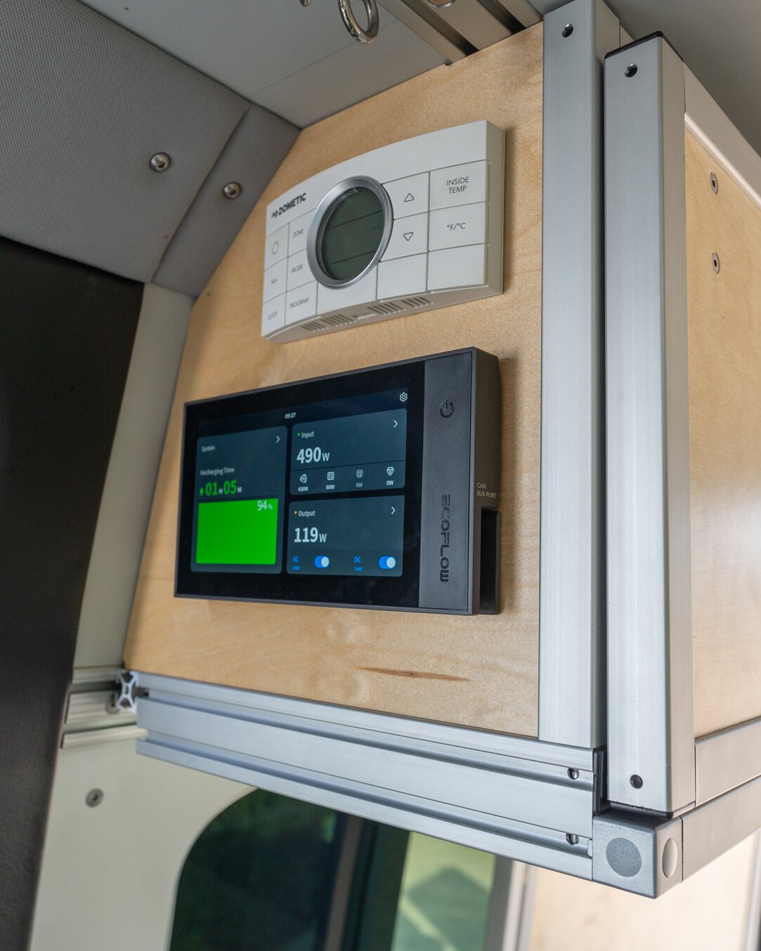 The camper van control center is on display. Atop the EcoFlow display console sits the Dometic Penguin II control and thermostat 