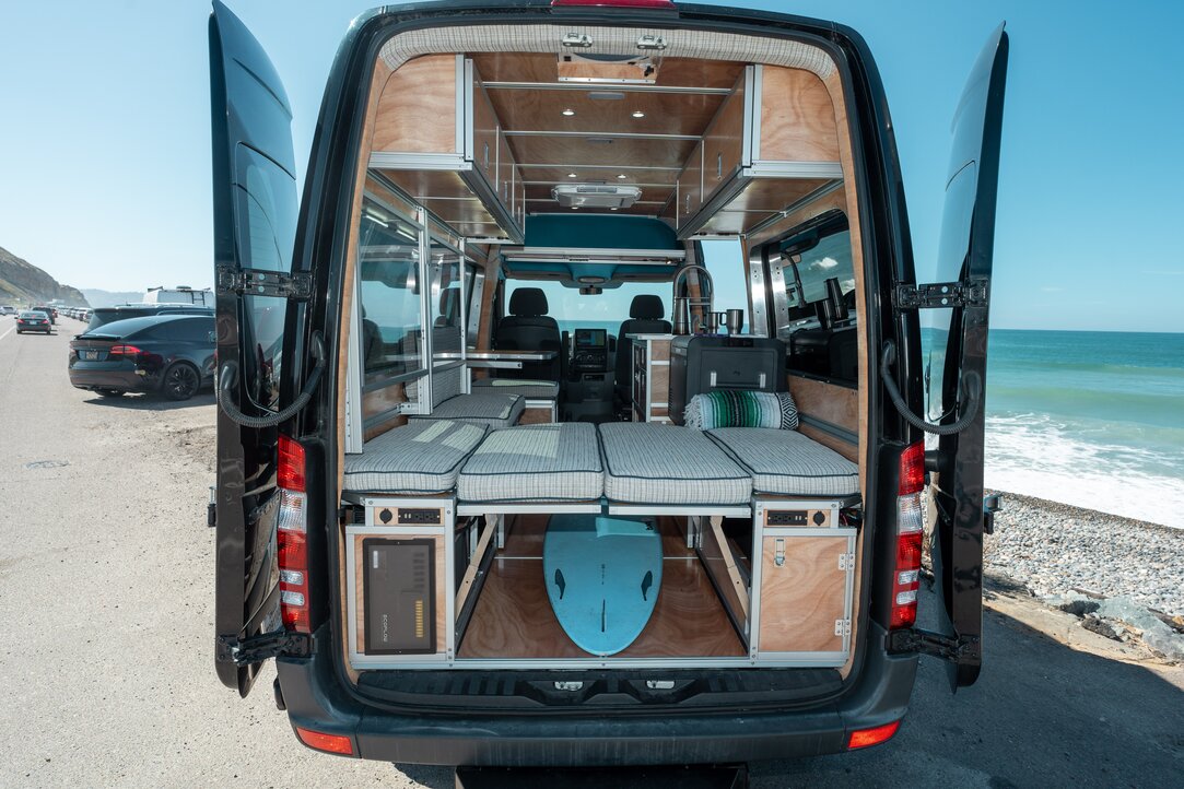Explore our full build of a Mercedes Sprinter 144 camper van featuring DIY systems. Discover clever storage solutions, including a surfboard tucked neatly under the bed.