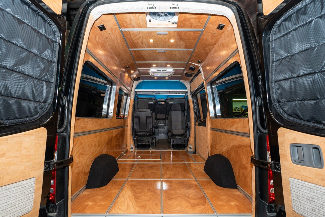 A woman enjoying a morning in her camper van kitchen, pouring coffee while admiring the ocean view. Experience serenity and convenience in our camper van.