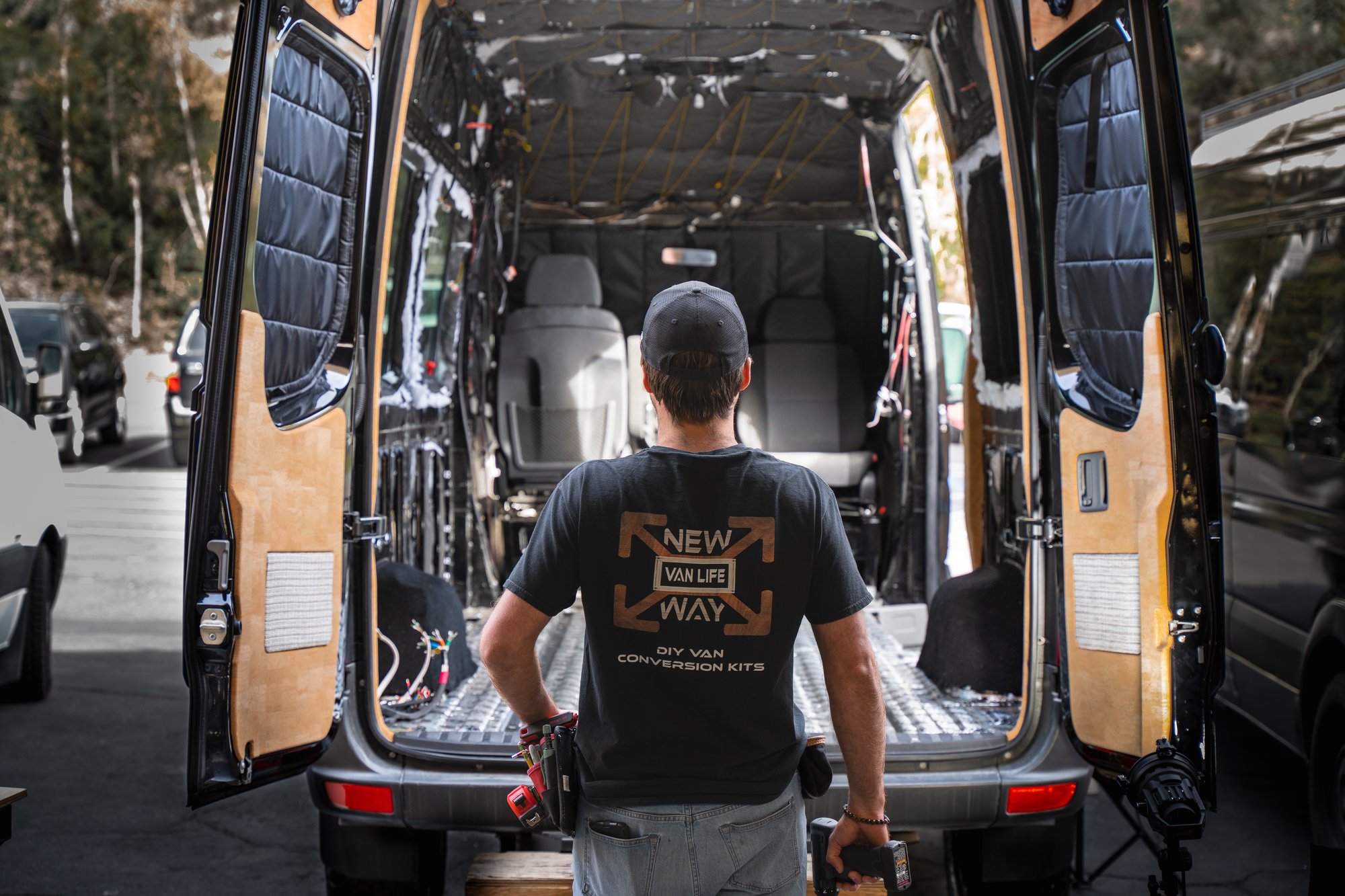 A van upfitter getting ready to install a modular interior system into a Mercedes Sprinter 144 sprinter van. The pre cut insulation and plug-and-play wiring harness are already installed.  