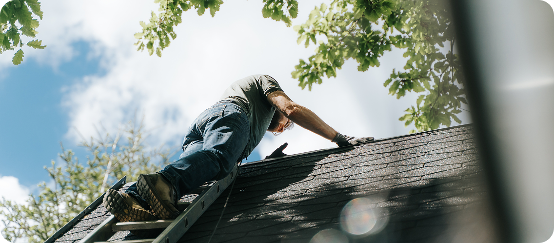 Someone on a ladder repairing a roof on a sunny day.
