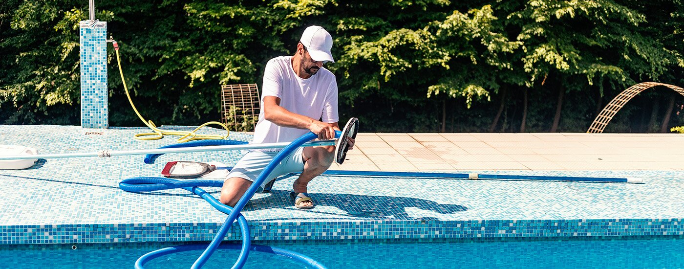 A homeowner performs preventative maintenance on their pool during a sunny day. 