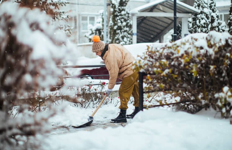 A person shovels snow in front of their home.