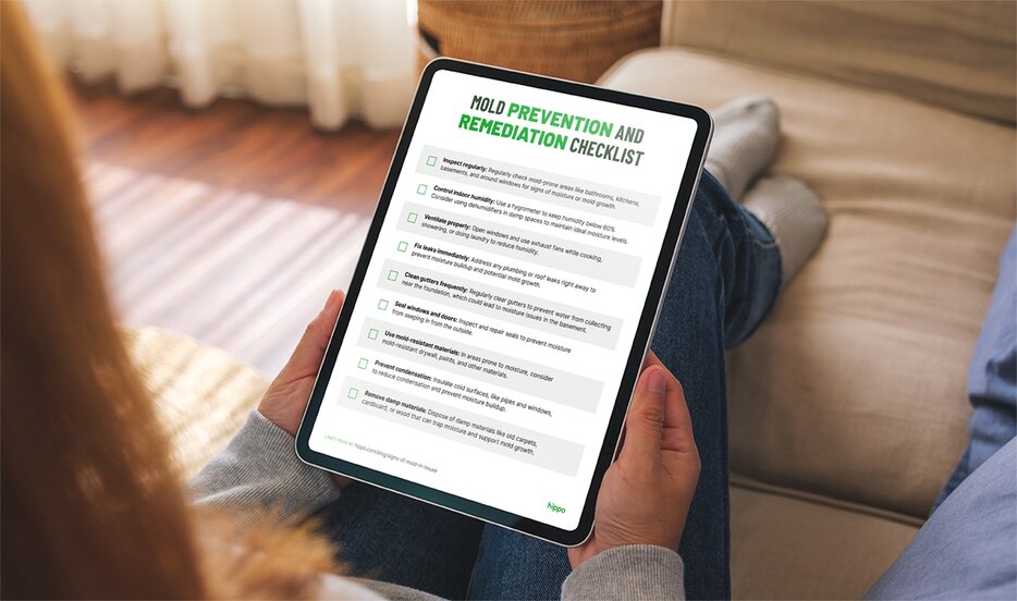 A homeowner holding a tablet reviewing a mold prevention and remediation checklist.