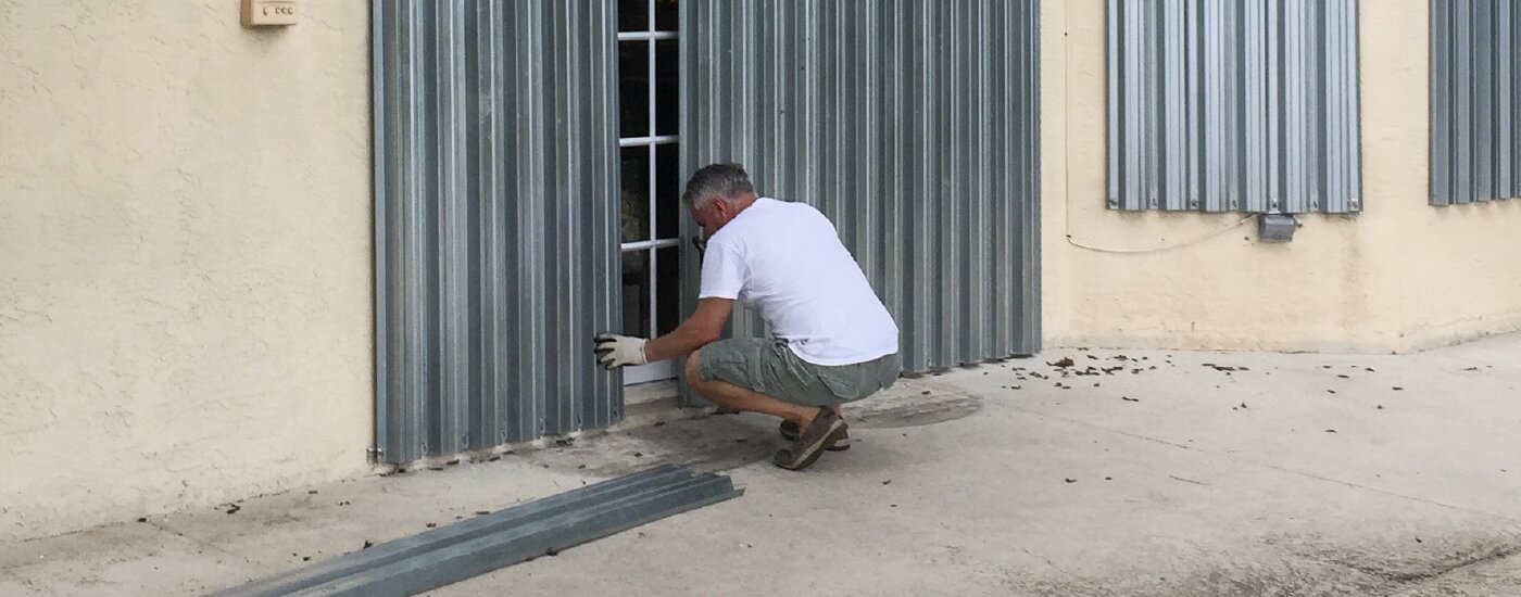 A homeowner boards up their home’s windows and doors in preparation for a storm