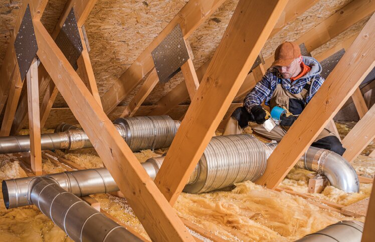 Homeowner repairs ventilation system during the winter season.