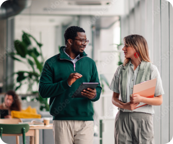 Two colleagues smiling and talking in a bright office environment.