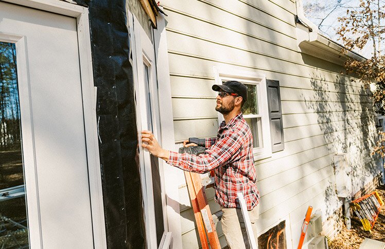 A man repairs the outside wall of his house.
