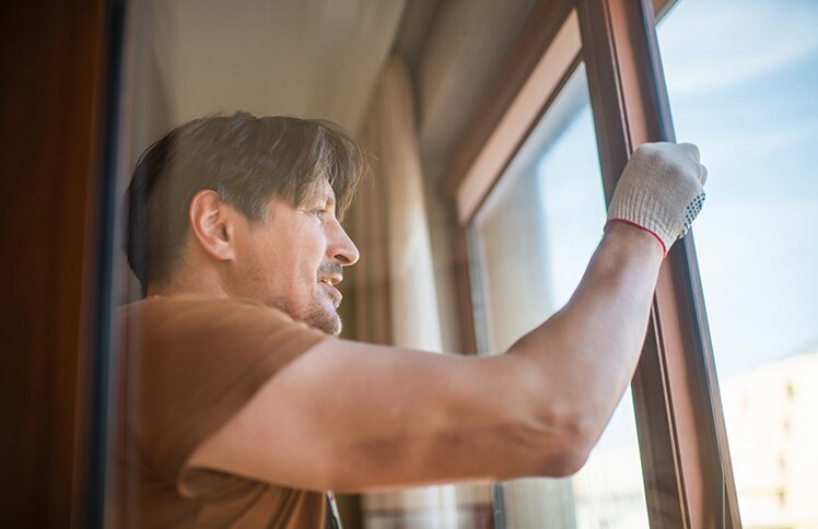  A middle-aged man installs new windows in his home.