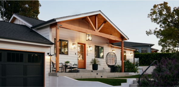 Front view of a house at evening with porch lights and window lights on