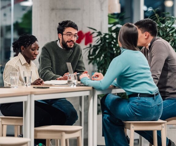 Three coworkers laughing and collaborating around a table.