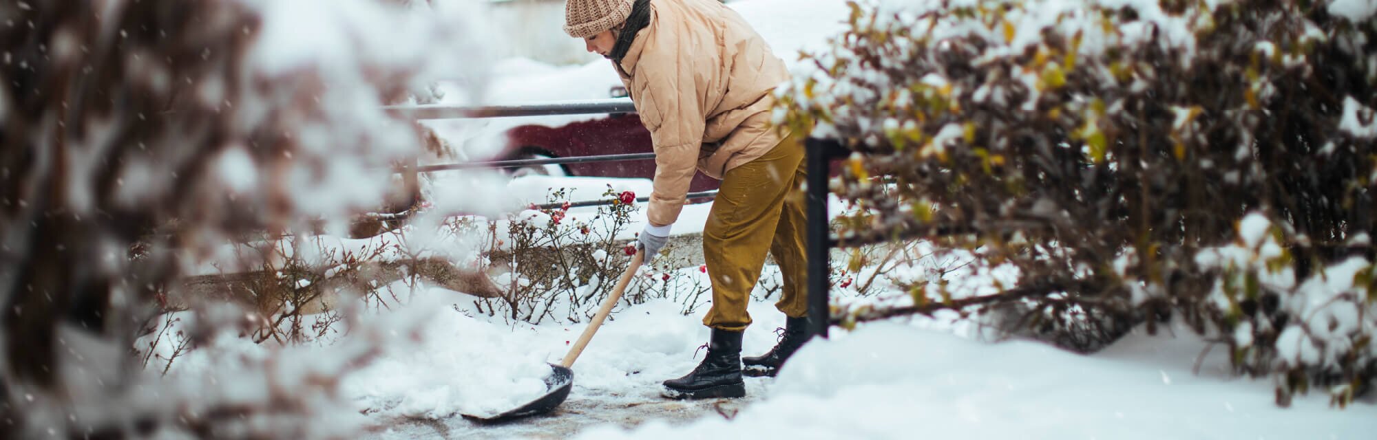 A person shovels snow in front of their home.