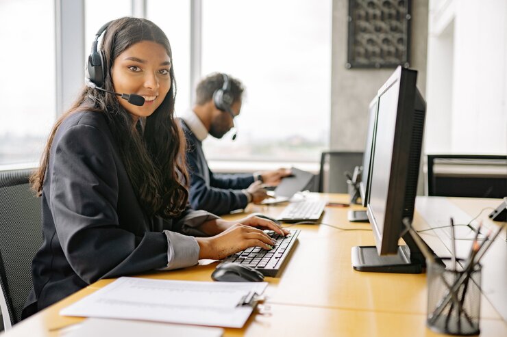 Customer service agents wearing headsets at computers.
