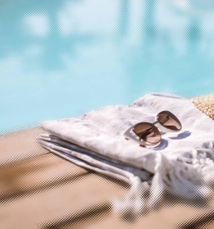 Picture of a sunglasses on a towel by a poolside