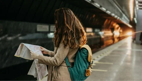 Female tourist waits for a train while checking a map