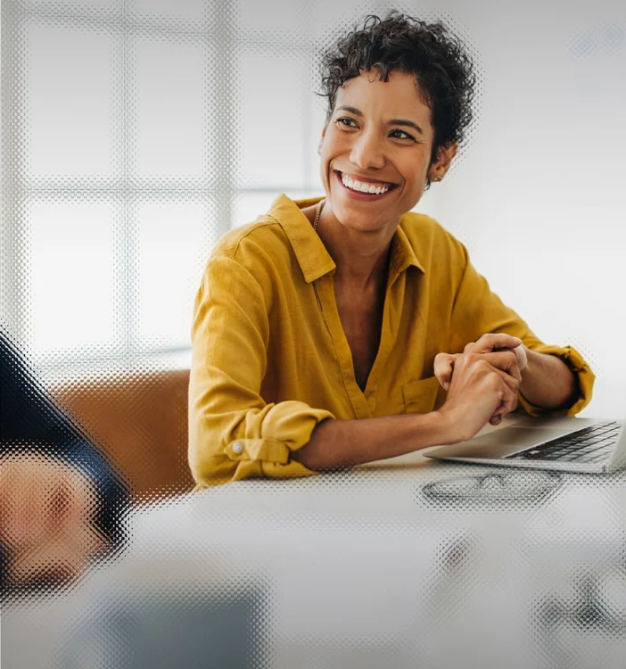 Picture of a woman at her desk with a laptop smiling