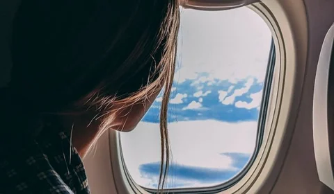 Traveler on phone looking out of plane window