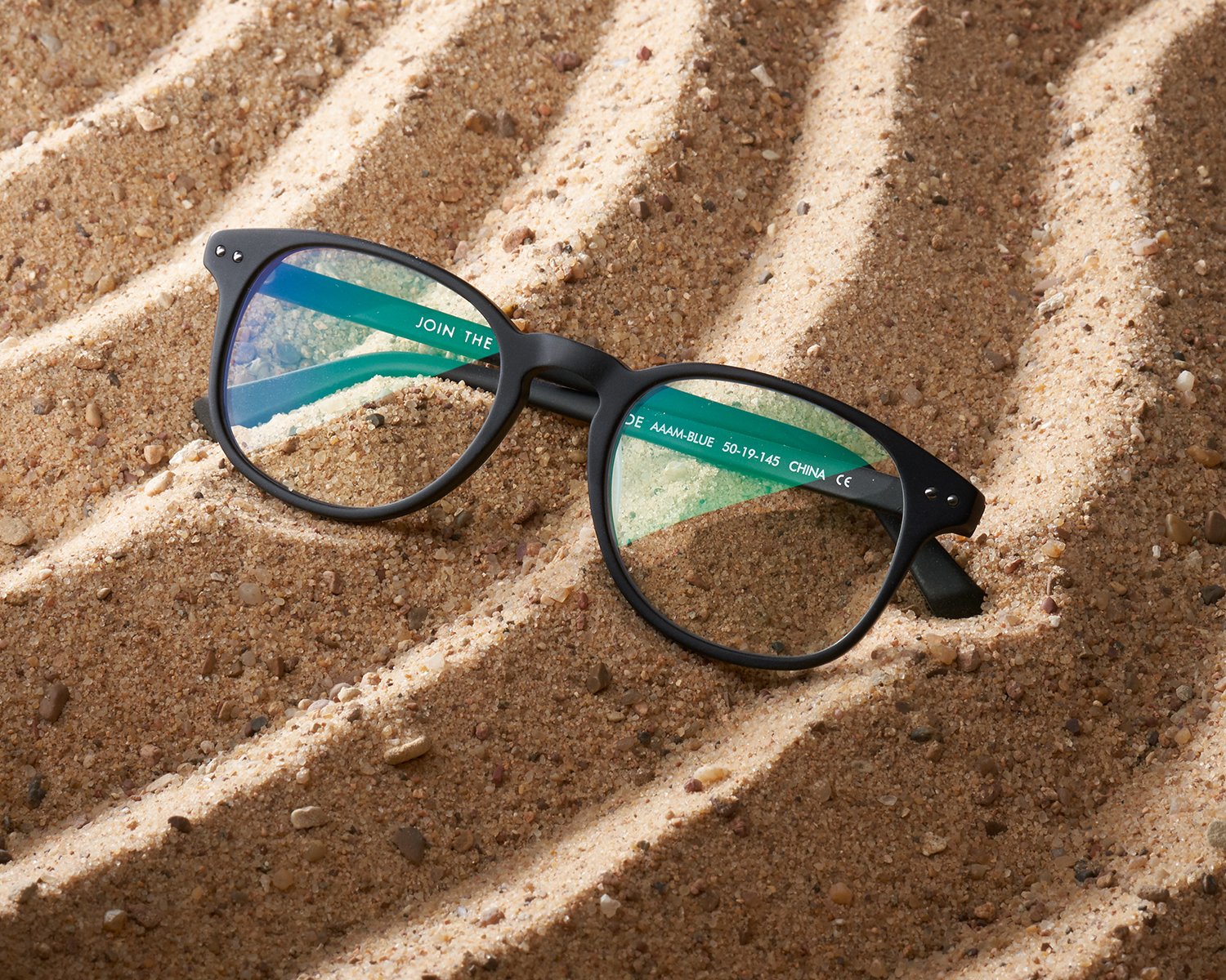 Gold & Black round sunglasses on green leaf background