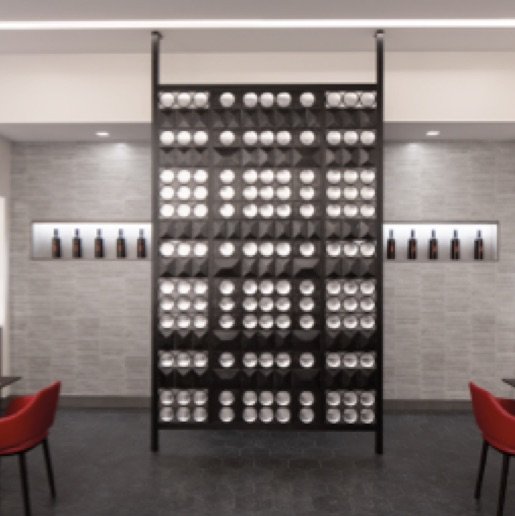 A black strip of wall with decorative glass globes and two walls with rectangular alcoves displaying wine bottles.