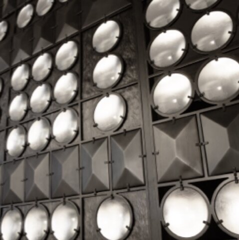 Opaque glass globes embedded in rows and raised trapezoidal pyramids in industrial black metal. 