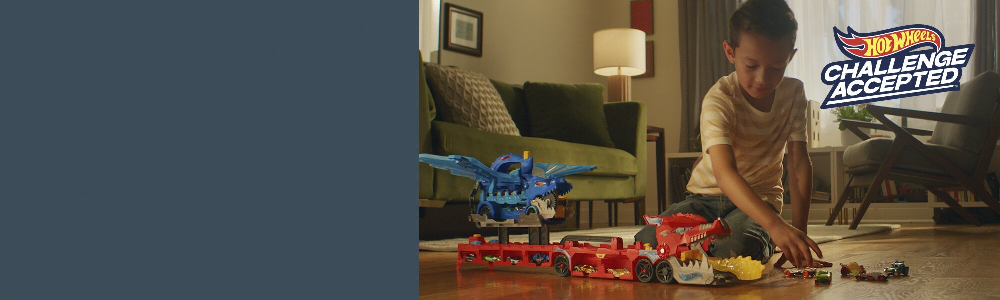 A boy playing with an assortment of Hot Wheels products. 