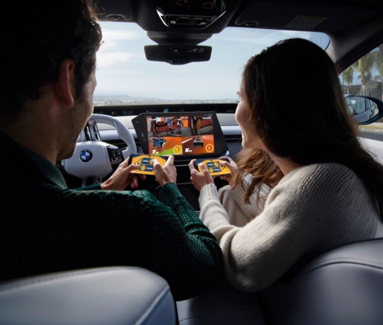 A picture depicting two people playing Hot Wheels: Xtreme Overdrive in a BMW