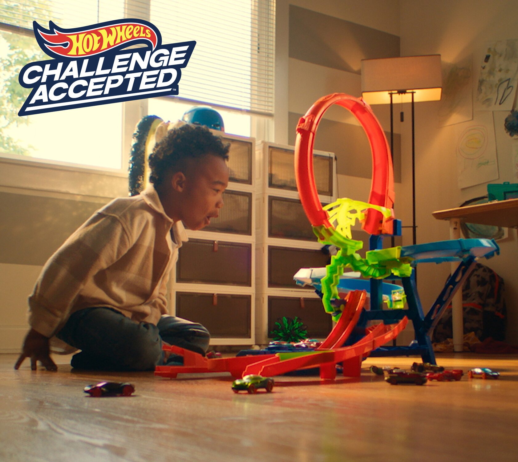 A boy playing with an assortment of Hot Wheels products. 