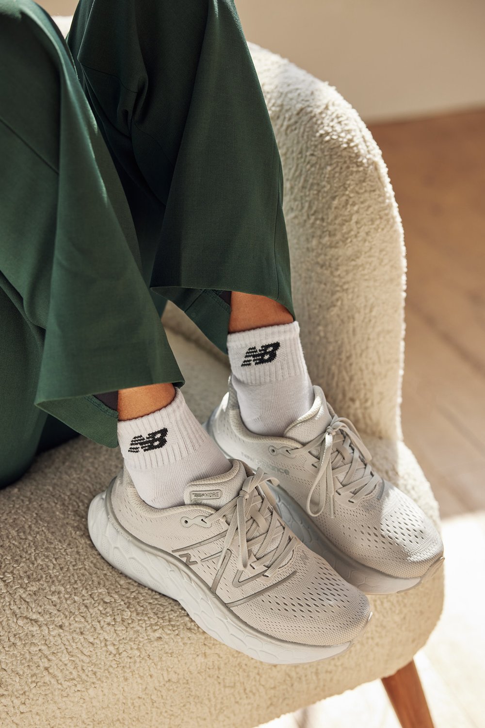 Clean white New Balance shoes and socks on a furry couch or chair. 
