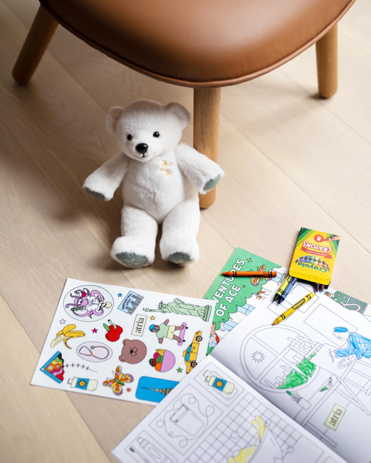 Branded and designed Atria coloring books for kids with Crayons and a white Teddy bear with a brand logo lockup