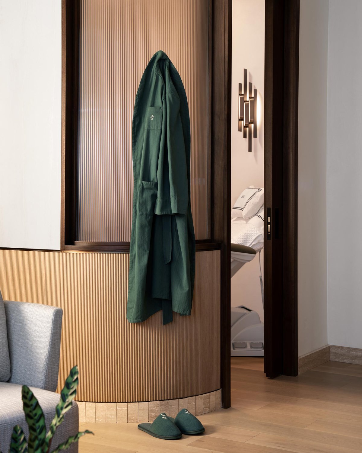 Branded green Atria robe and comfortable slippers in a healthy spa environment with wood floors and wall paneling. 