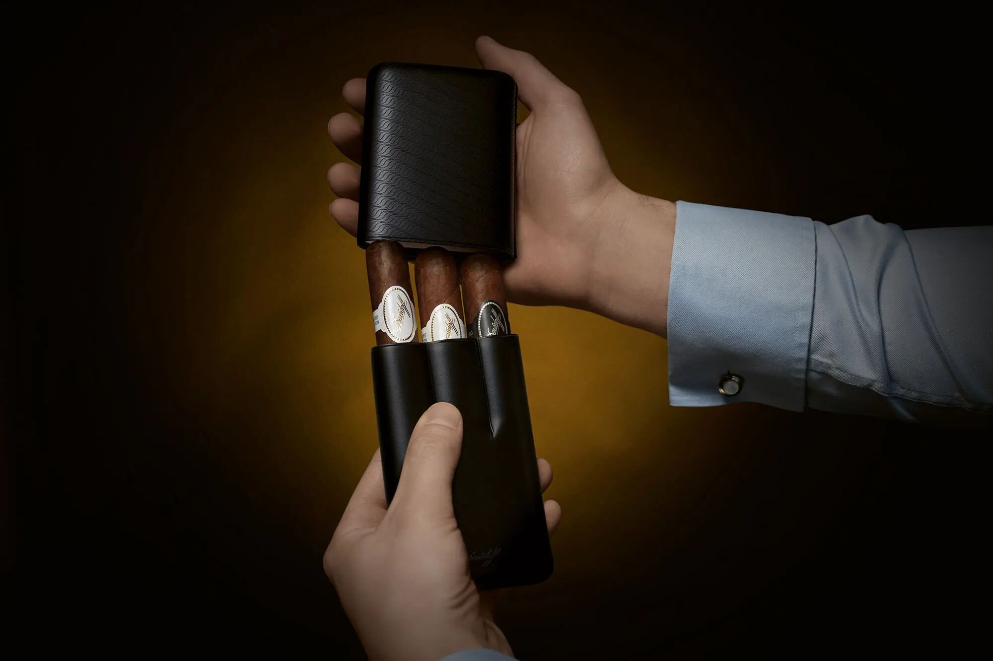 Close-up of hands opening a Davidoff Cigar Case with Davidoff cigars in it.