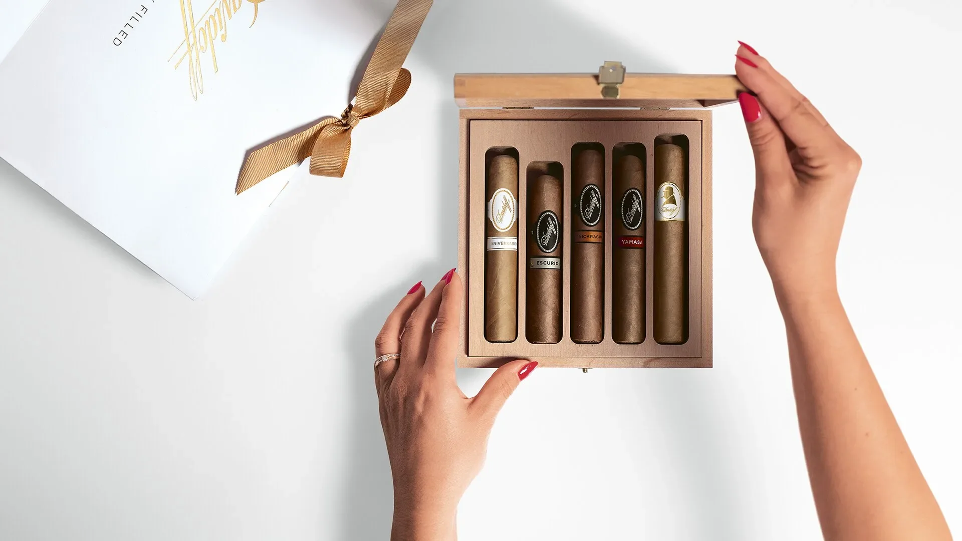 Top view of women hand opening a box of Davidoff Cigar Assortment box with a Aniversario, Escurio, Nicaragua, Yamasà and Winston Churchill cigar