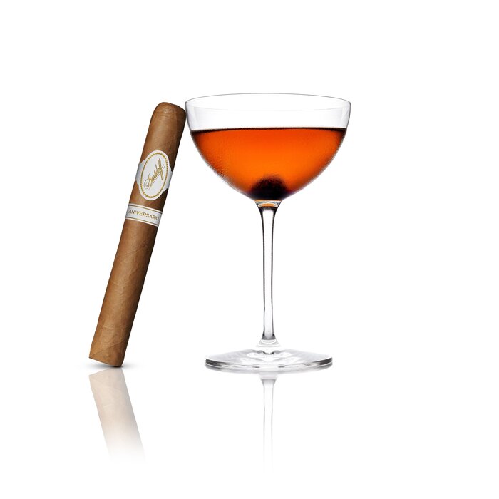 An Begroni Cocktail served in a Winston Churchill glass, with an Aniversario No. 3 cigar elegantly leaning against the glass, highlighting a refined pairing of drink and luxury cigar.