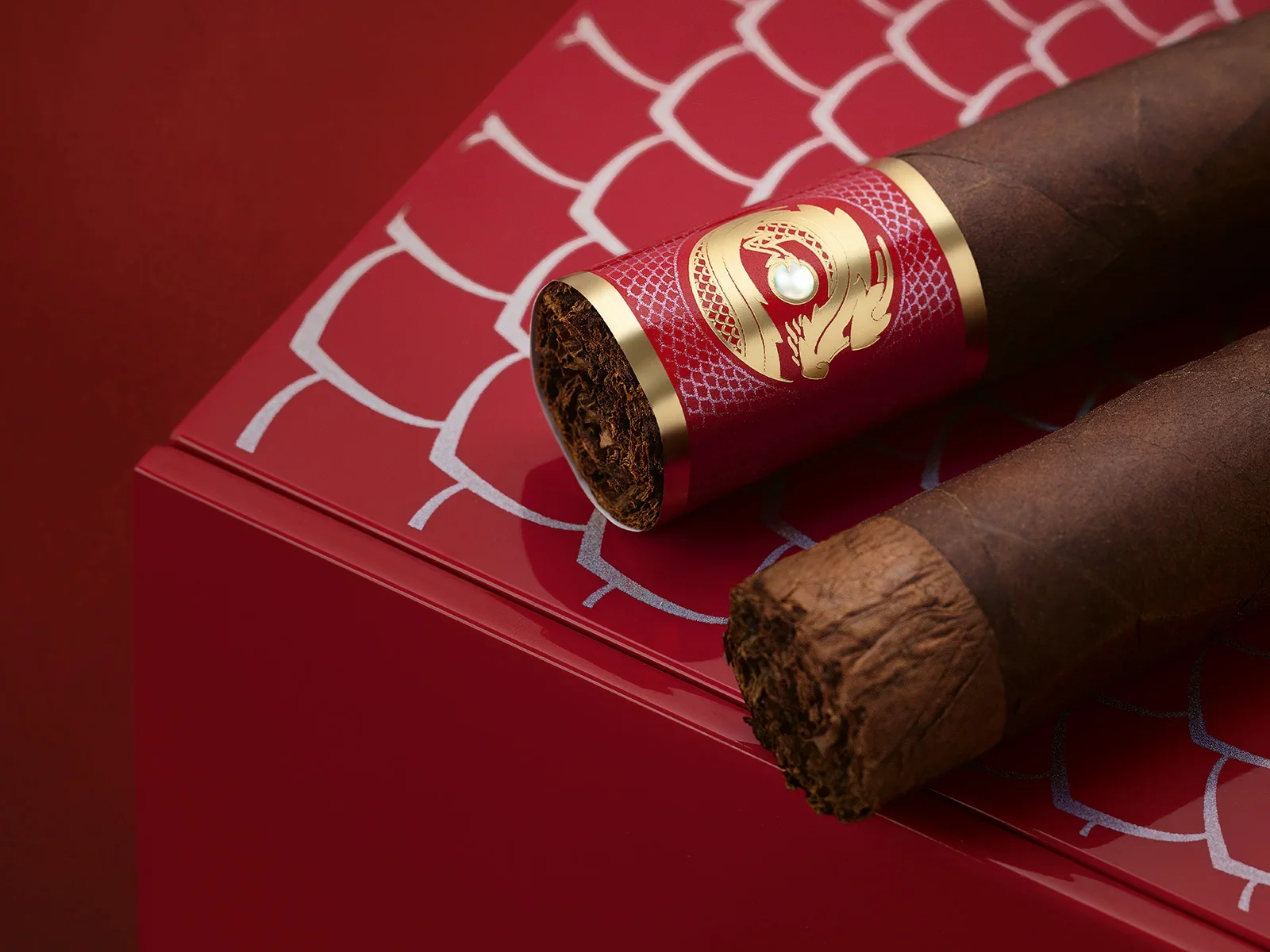 Detailshot of 2 Davidoff Year of the Dragon cigars, one with the foot ring and one without on top of the cigar box 