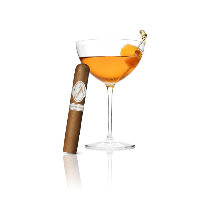 An Sweet and Spice Cocktail served in a Winston Churchill glass, with an Davidoff Nicaragua Toro cigar elegantly leaning against the glass, highlighting a refined pairing of drink and luxury cigar.