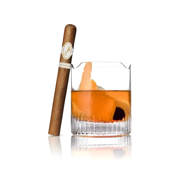Bourbon Pie cocktail with orange twist and cherry beside a Davidoff Aniversario Double R cigar.