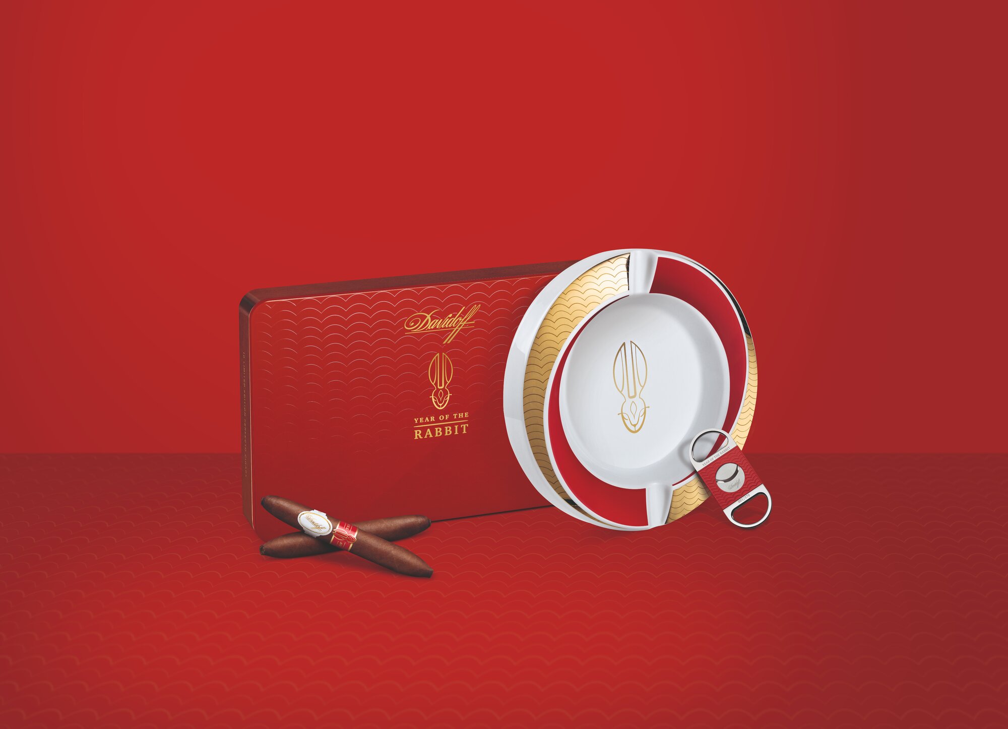 Two Davidoff Year of the Rabbit Limited Edition cigars crossed lying in front of their red box, next to them are the Year of the Rabbit ashtray and the Year of the Rabbit cutter.