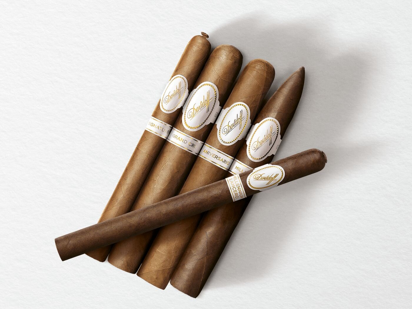 4 cigars of the Davidoff White Band Collection lines Signature, Grand Cru, Millennium and Aniversario with one Davidoff Millennium Lancero Limited Edition Collection cigar placed across on top of them.