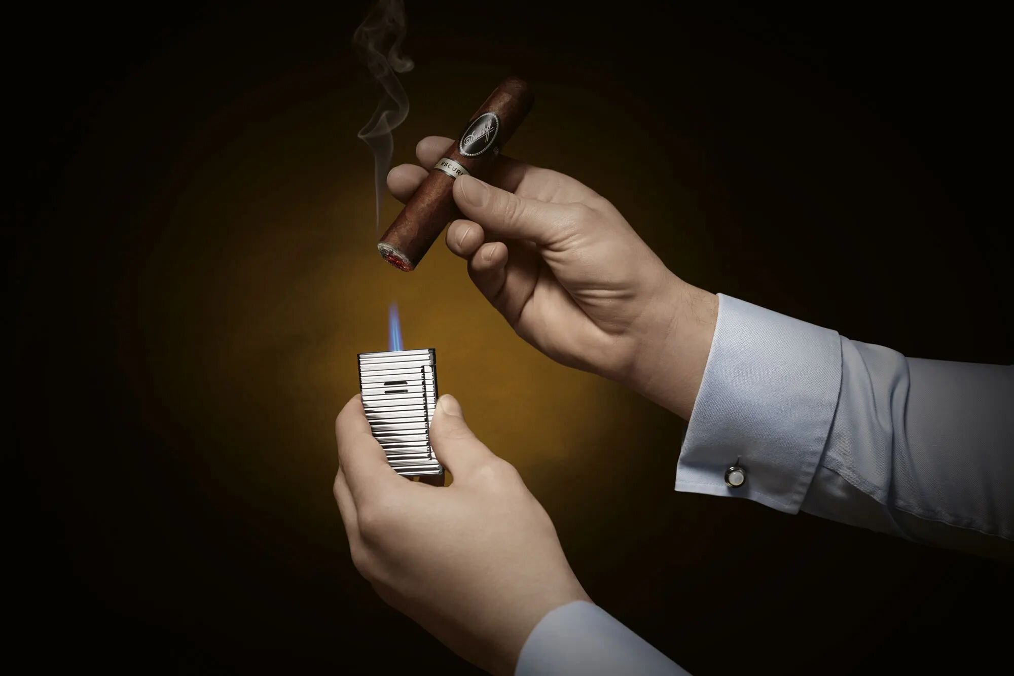 Close-up of a hand lighting a Davidoff White Band cigar with a Davidoff Jet Flame Palladium lighter