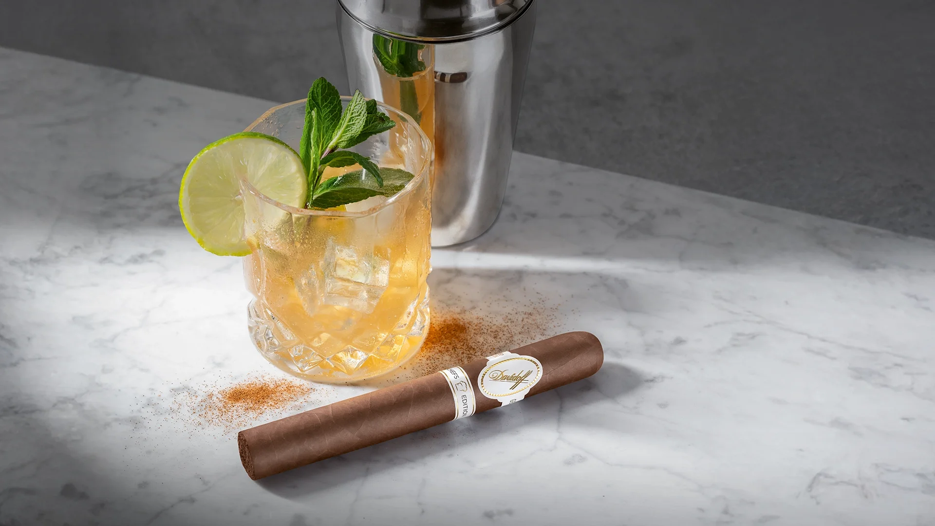 A Davidoff Chefs Edition 2025 cigar next to a glass of Virgin Moscow Mule with a shaker in the background.
