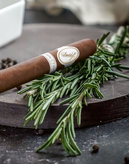 Davidoff Chefs Edition 2021 Churchill Cigar on a chopping board with rosemary and pepper.