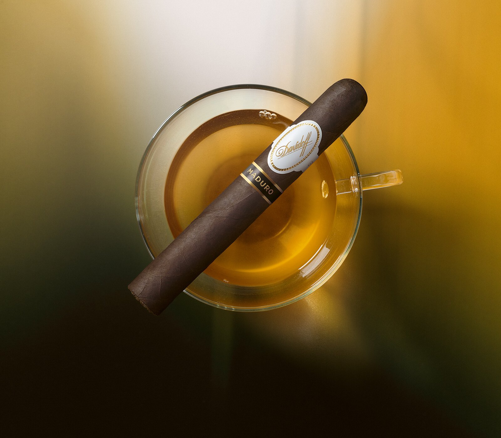 A Davidoff Dominicana cigar leaning on a glass of rum