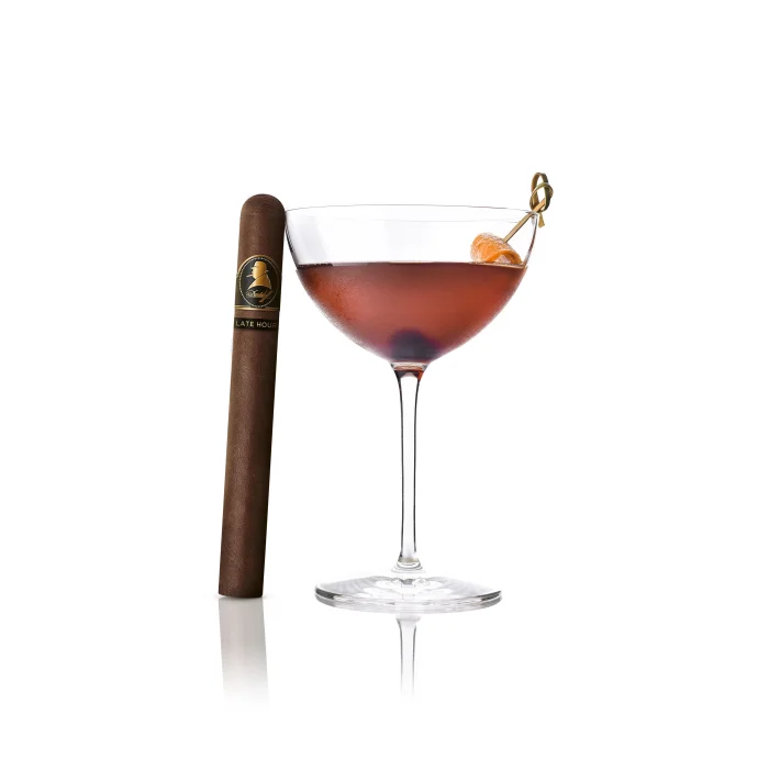 Late Hour Winston Churchill cigar next to a red Late Night Coffee cocktail with orange twist.