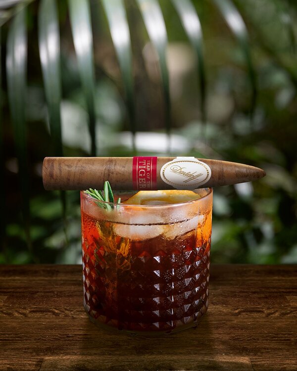 Davidoff Year of the Tiger limited edition piramides cigar lying on top of a glass with a rum based cocktail.