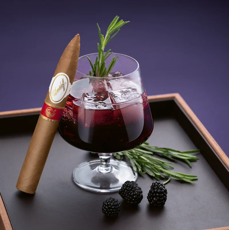 The Year of the Sheep piramides cigar leaning on a glass with Blackberry Vanilla Cream Fizz.