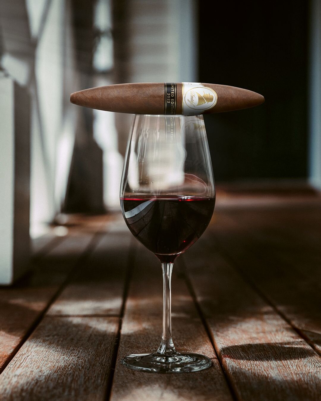 Filled portwine glass with Davidoff Winston Churchill Limited Edition 2022 perfecto cigar resting on top.