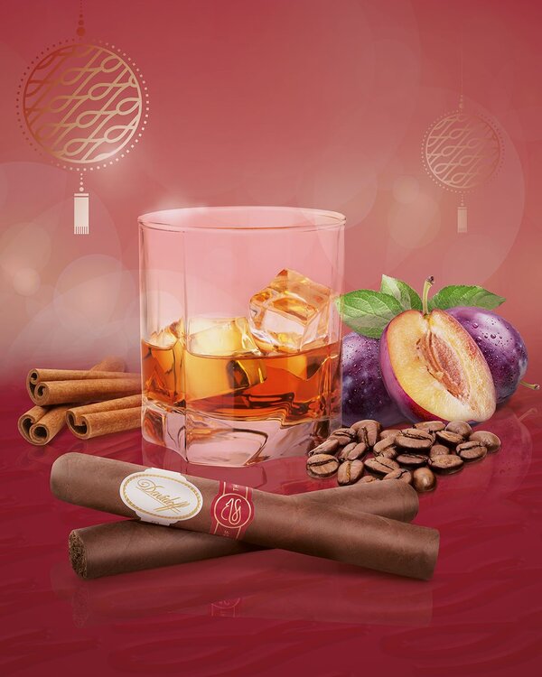 A glance reveals a glass filled with ice cubes and whisky, accompanied by plums, cinnamon, and roasted coffee. Two cigars are elegantly crossed in front of the glass.